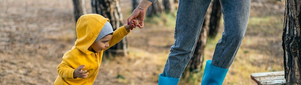 An adult holding the hand of a small child